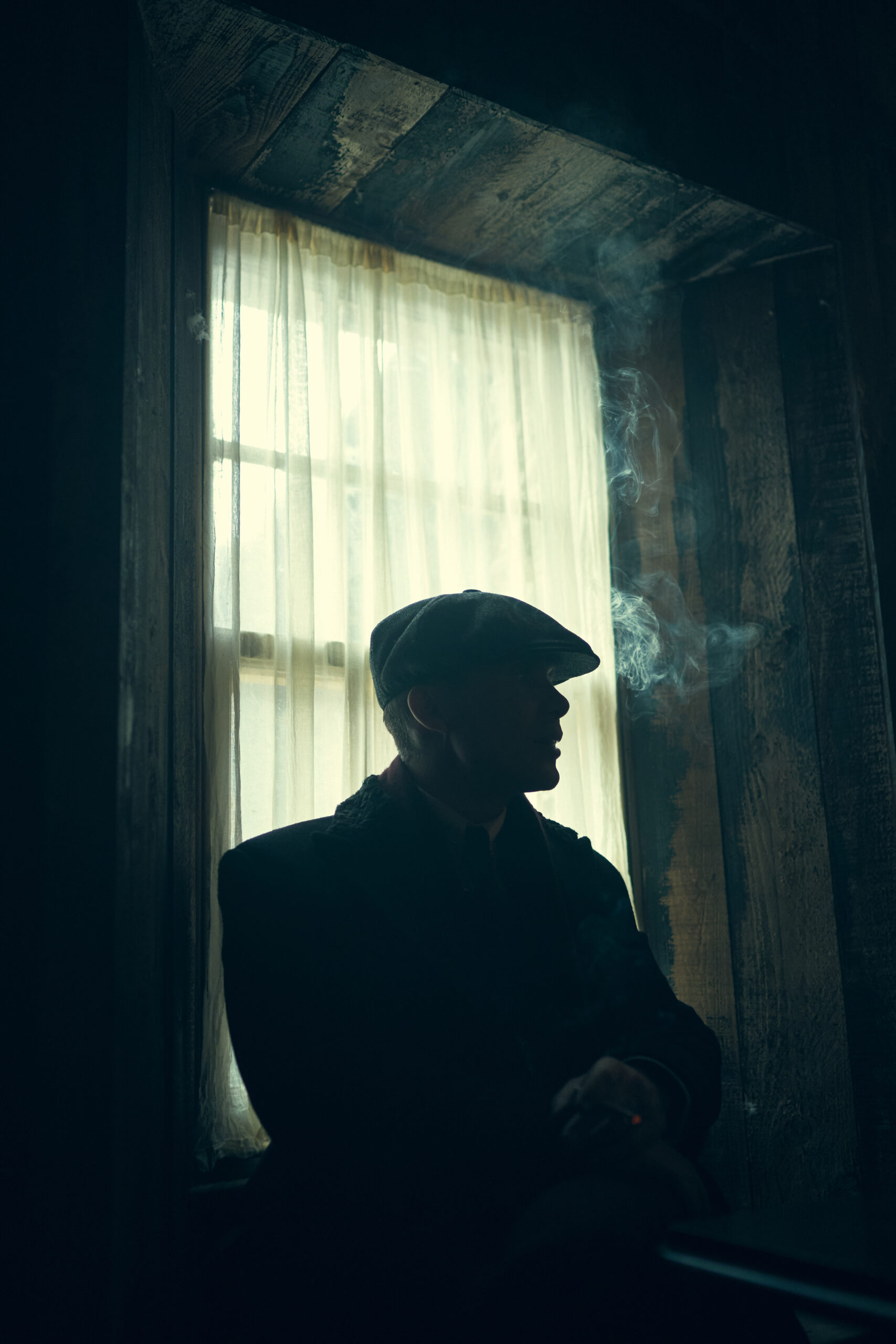 Tommy Shelby smoking by a window in Peaky Blinders Season 6