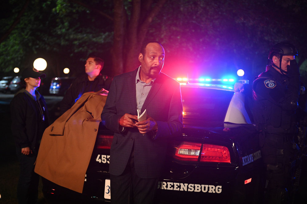 Still from the Irrational Season 1 Episode 1 of Jesse L. Martin as Alec Mercer leaning against the back of a police car
