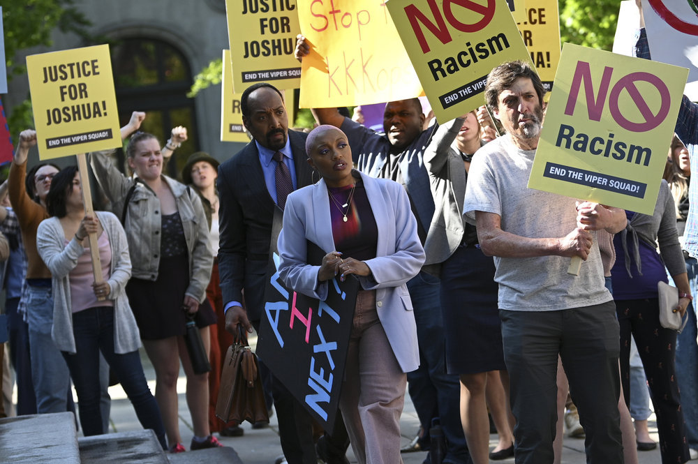 Still from The Irrational Season 1 Episode 6 of Jesse L. Martin as Alec Mercer, Travina Springer as Kylie, and protesters pictured from left to right.