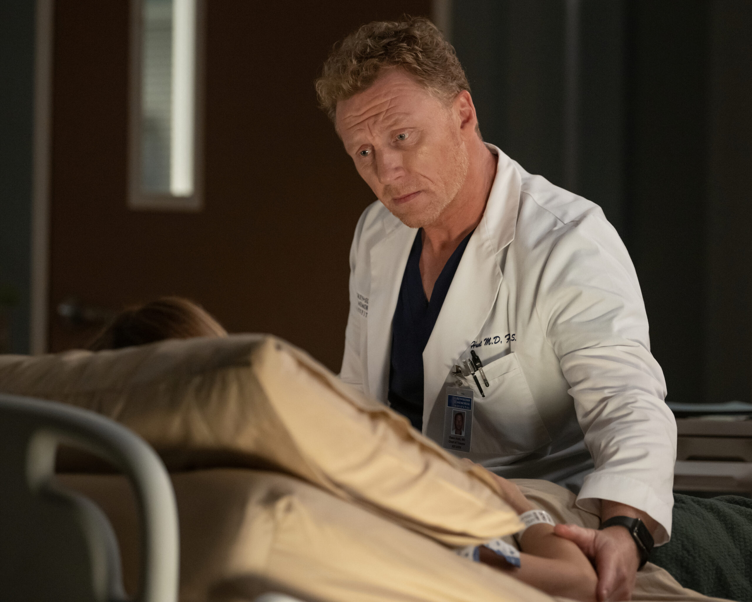 Owen sits with Teddy in her hospital bed. Grey's Anatomy Season 20 Episode 2, "Keep the Family Close."