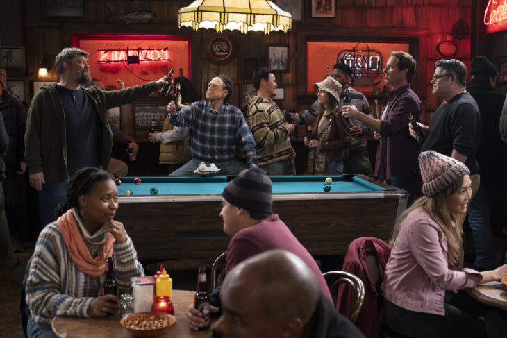 The Conners Season 6 Episode 6 - JAY R. FERGUSON, JOHN GOODMAN, NAT FAXON, SEAN ASTIN drinking beers and playing pool at a bar.