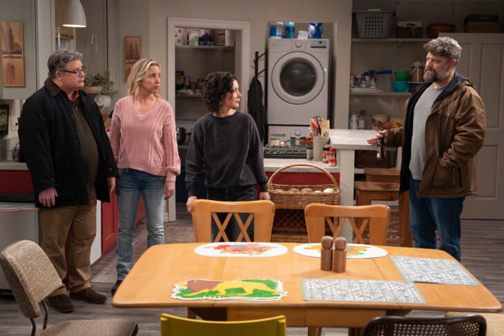 The Conners Season 6 Episode 6 - SEAN ASTIN, LECY GORANSON, SARA GILBERT, JAY R. FERGUSON all stand in the kitchen of Darlene and Ben's home. Ben stands away from the rest looking upset about something they've said.