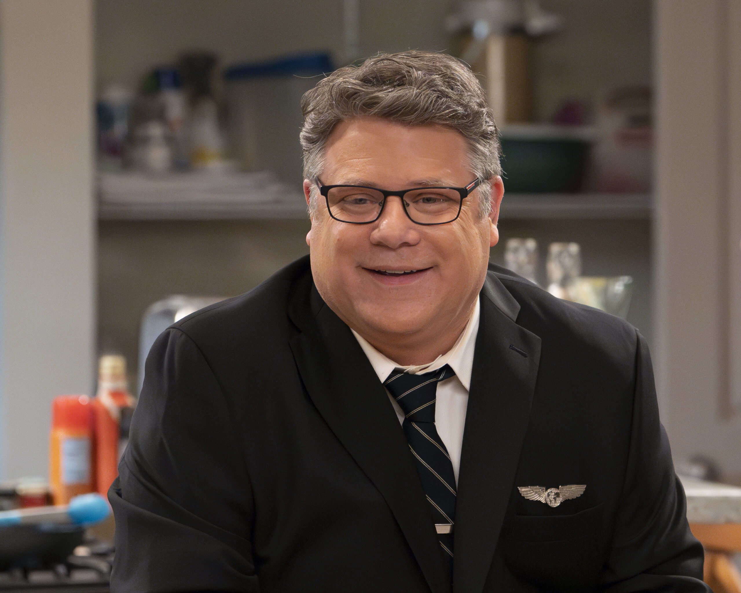 The Conners Season 6 Episode 6 - SEAN ASTIN. Tyler smiles while wearing his pilot's uniform.