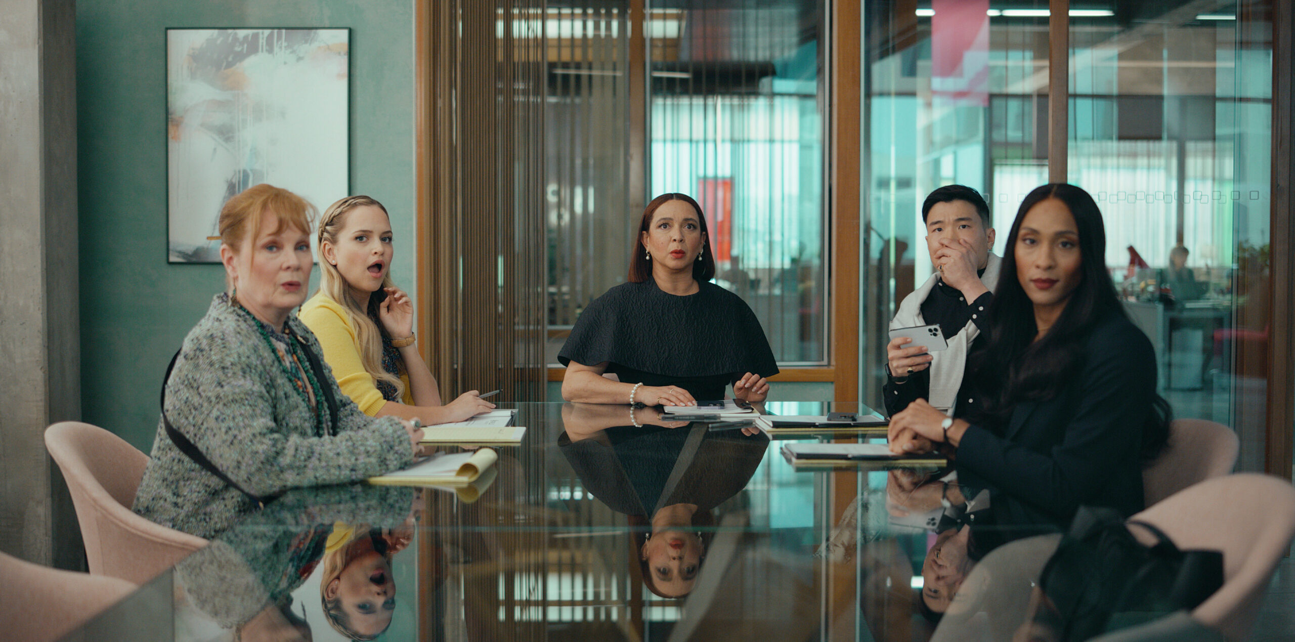 Loot Season 2 Episode 2 - Meagen Fay, Stephanie Styles, Maya Rudolph, Joel Kim Booster and Michaela Jaé Rodriguez | Tell-Tale TV Still from Loot Season 2 Episode 2 of Meagen Fay, Stephanie Styles, Maya Rudolph, Joel Kim Booster and Michaela Jaé Rodriguez sitting from left to right at a conference table.