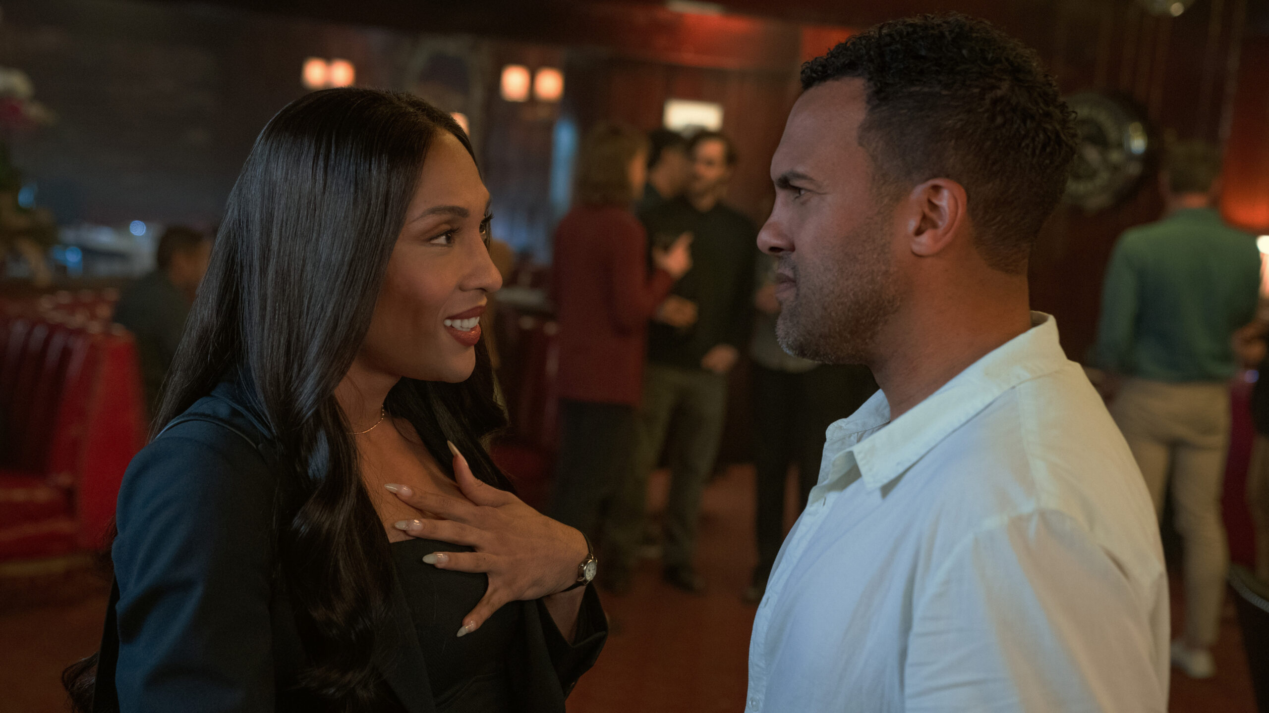 Still from Loot Season 2 Episode 2 of Michaela Jaé Rodriguez wearing a black shirt and jacket and O-T Fagbenle wearing a white shirt in a medium sot facing each other from left to right.