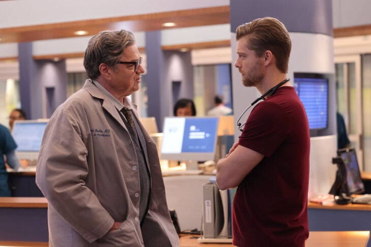 Chicago Med Season 9 Episode 7 Oliver Platt as Dr. Daniel Charles stands talking to Luke Mitchell as Dr. Mitch Ripley.