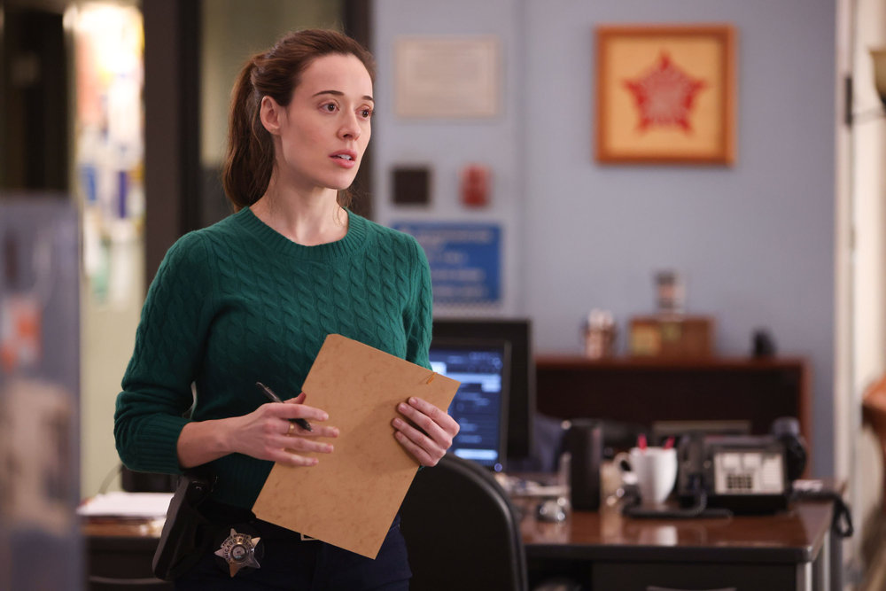Chicago P.D. - Season 11 Episode 8 Marina Squerciati stands with a case file in hand.