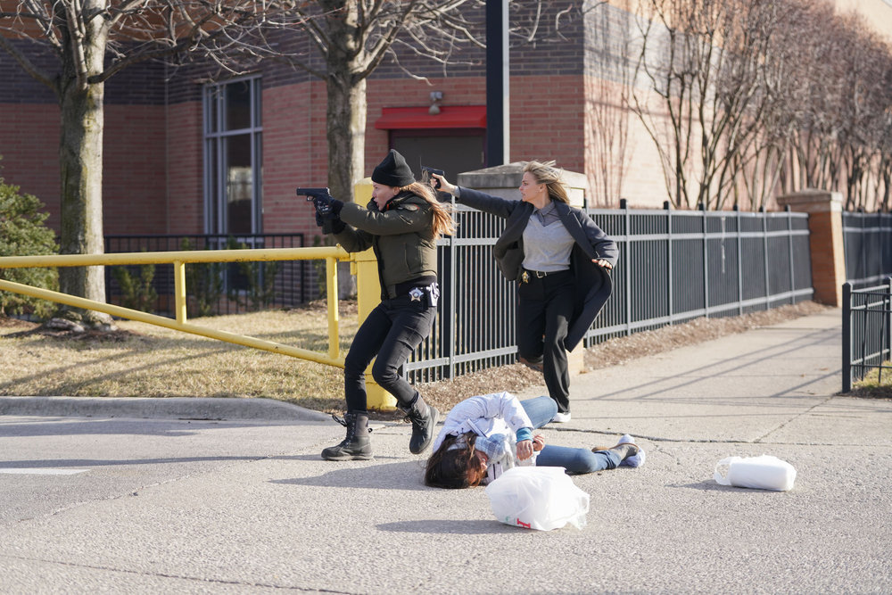 Chicago P.D. - Season 11 Episode 8 Bojana Novakovic runs a few paces behind Tracy Spiridakos as Hailey Upton. Both women have their guns drawn.