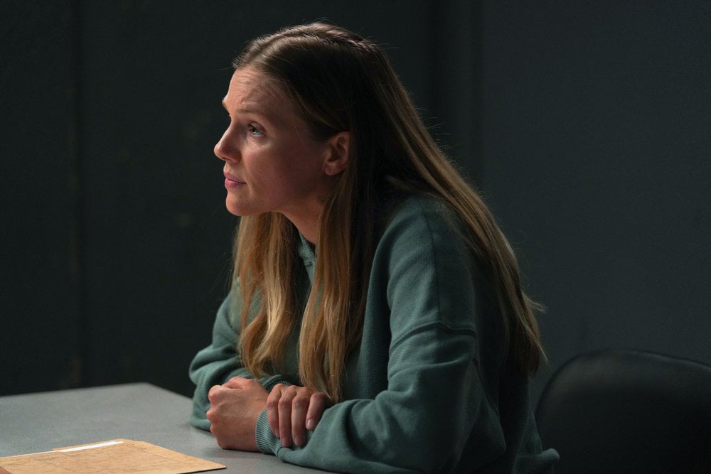 Chicago P.D. - Season 11 Episode 8 Tracy Spiridakos as Hailey Upton sits at an interrogation table looking intensely at someone out of frame.