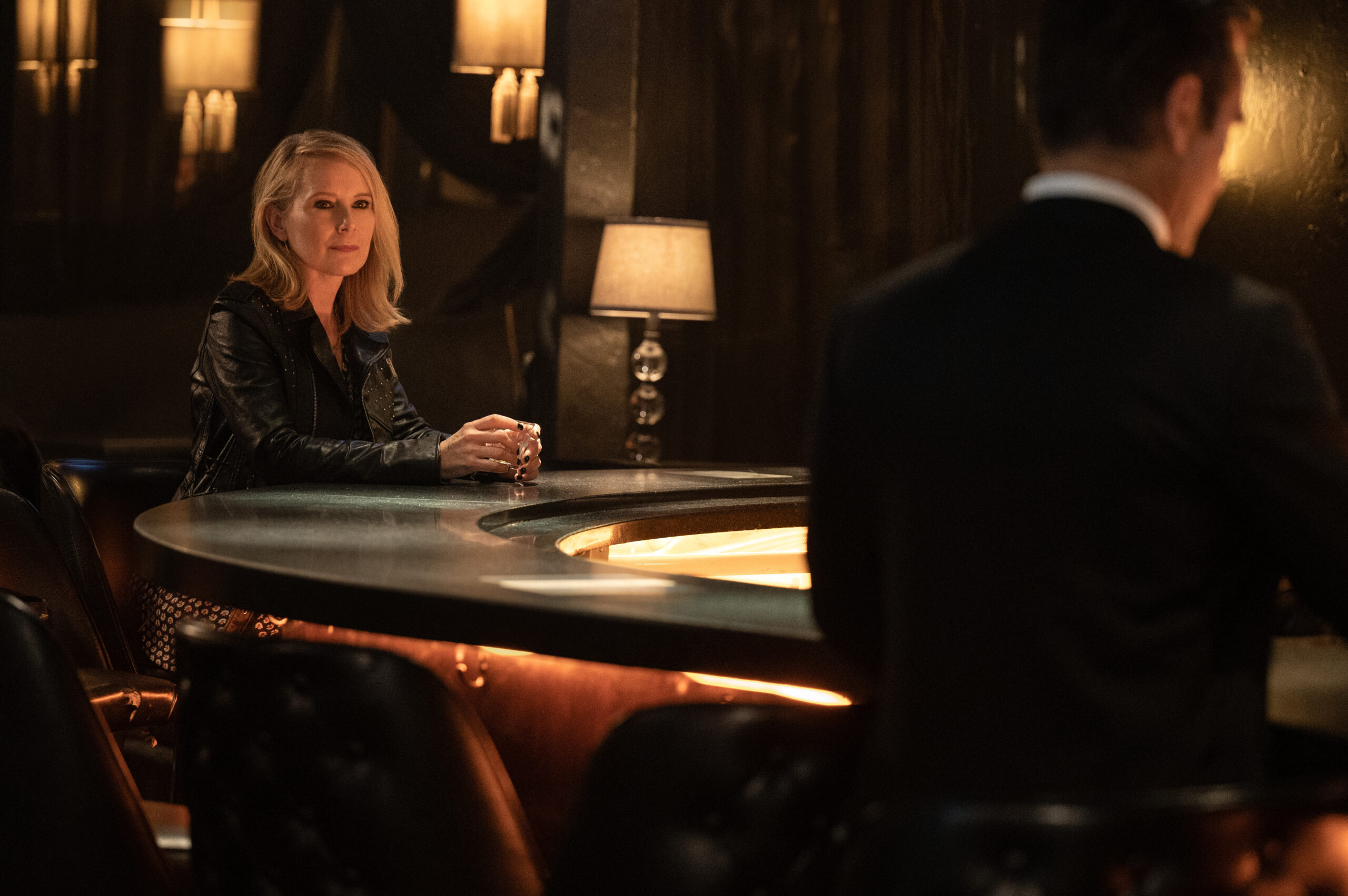 Still from Sugar Season 1 Episode 1 of Amy Ryan and Colin Farrell sitting across from each other at a bar from left to right.