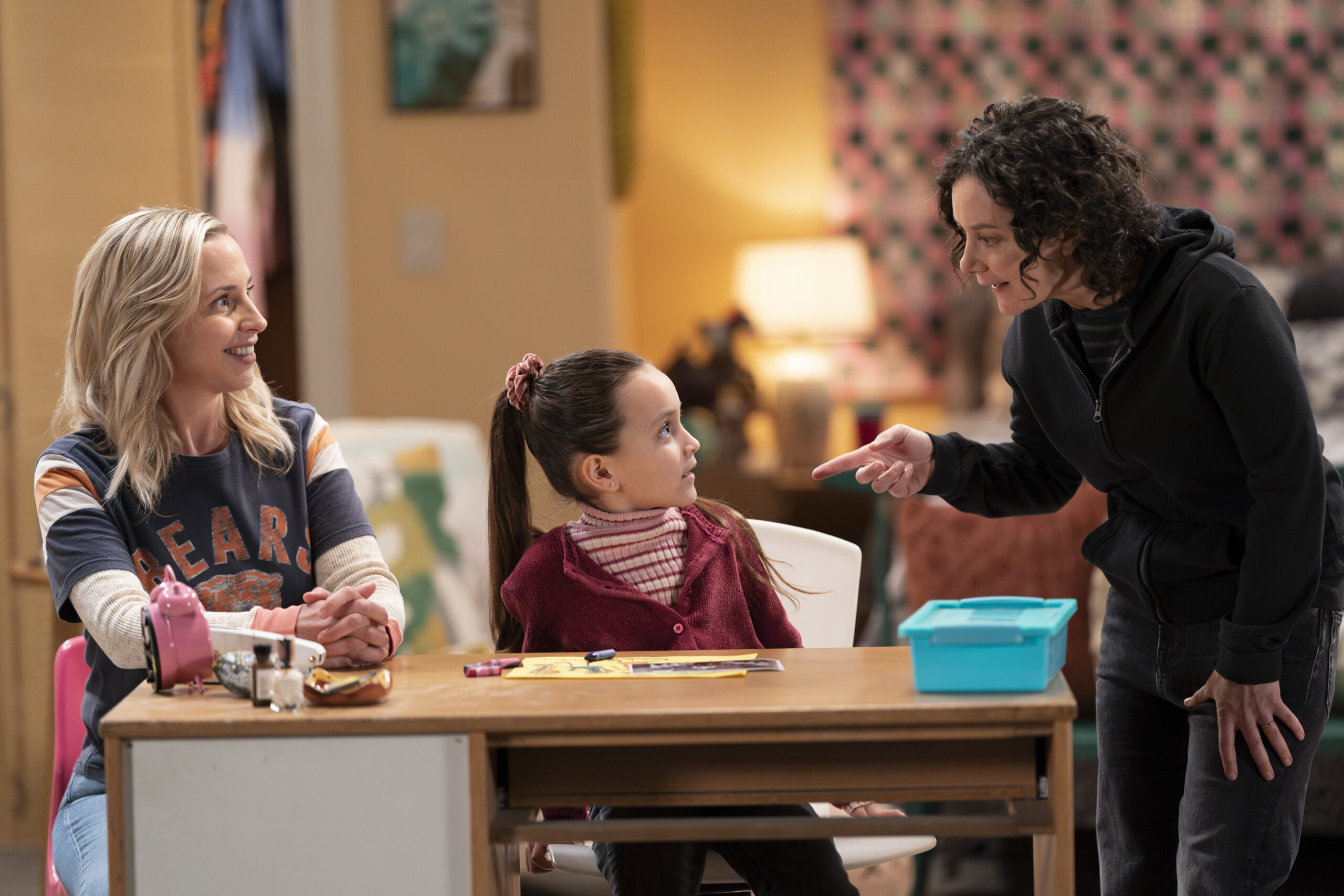 The Conners Season 6 Episode 7: LECY GORANSON, CHARLOTTE SANCHEZ, SARA GILBERT in Beverly Rose's room talking.