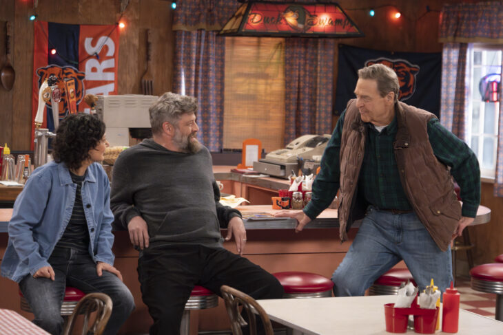 The Conners Season 6 Episode 10 - SARA GILBERT, JAY R. FERGUSON and JOHN GOODMAN all sit at the counter of the Lunch Box while talking.