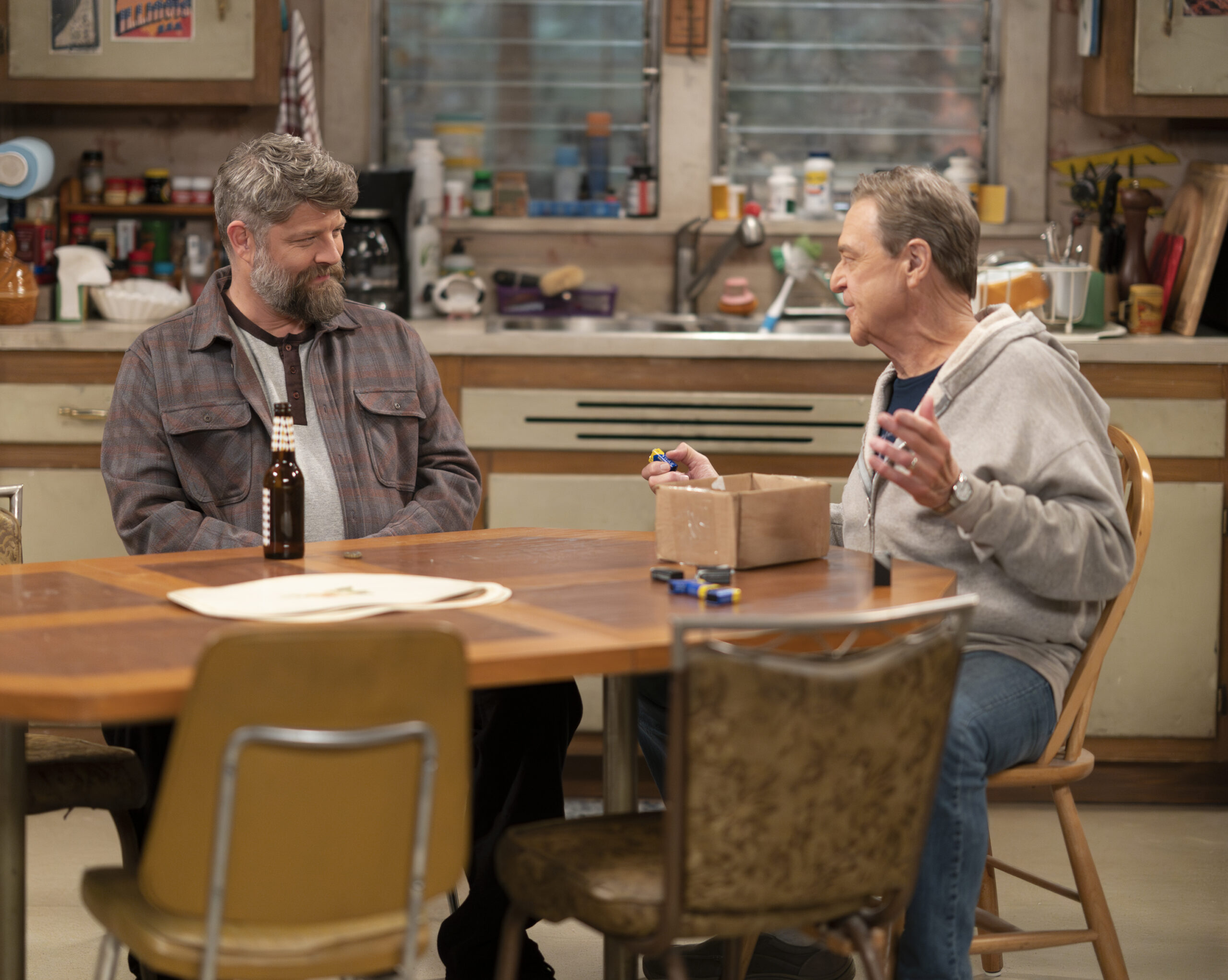 JAY R. FERGUSON, JOHN GOODMAN | Tell-Tale TV The Conners Season 6 Episode 10 - JAY R. FERGUSON and JOHN GOODMAN sit at the Conner family kitchen table talking.