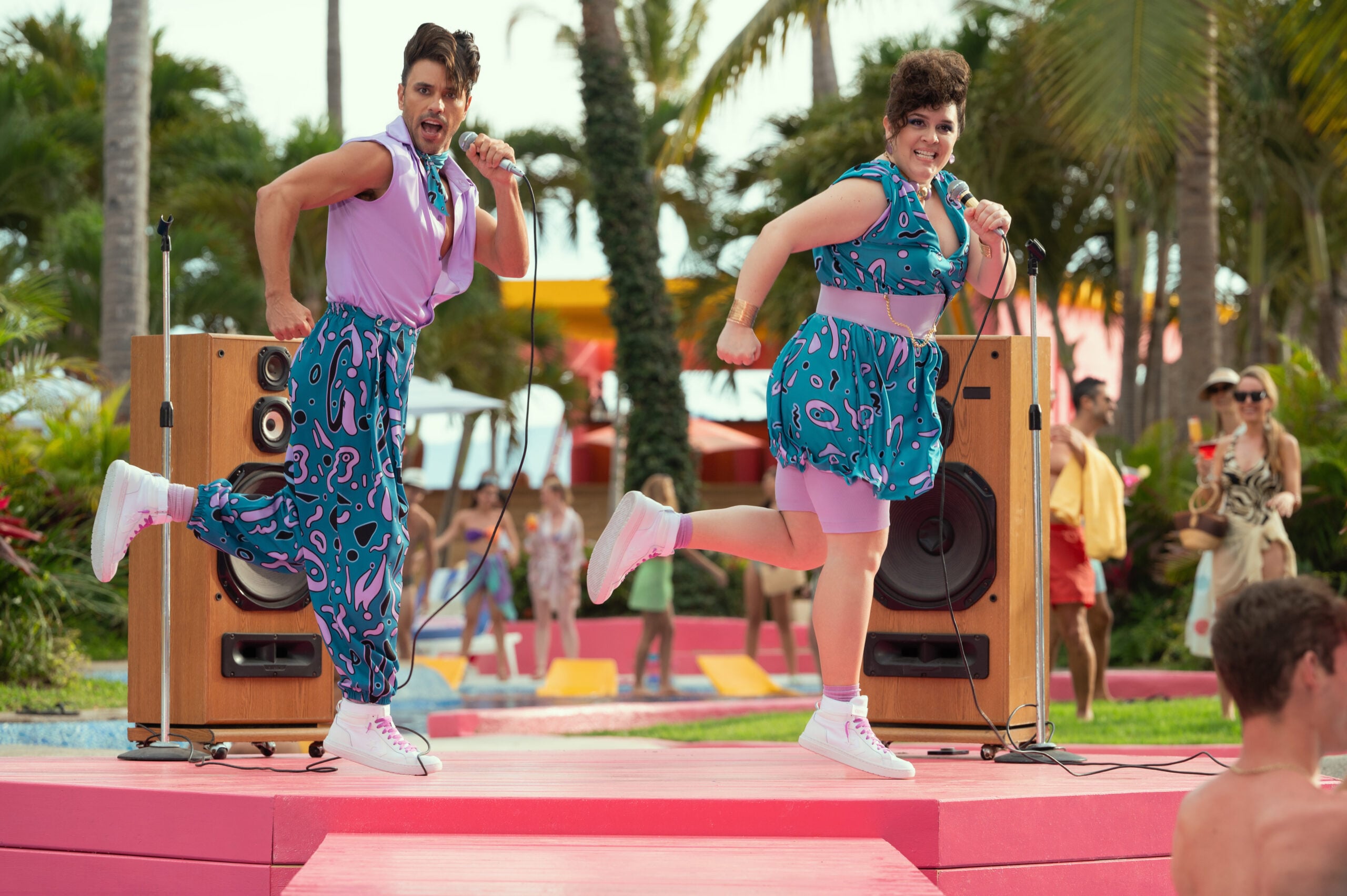 Still from Acapulco Season 3 Episode 1 of Rodrigo Urquidi and Rosanna De Leon performing outside on a red stage pictured from left right.