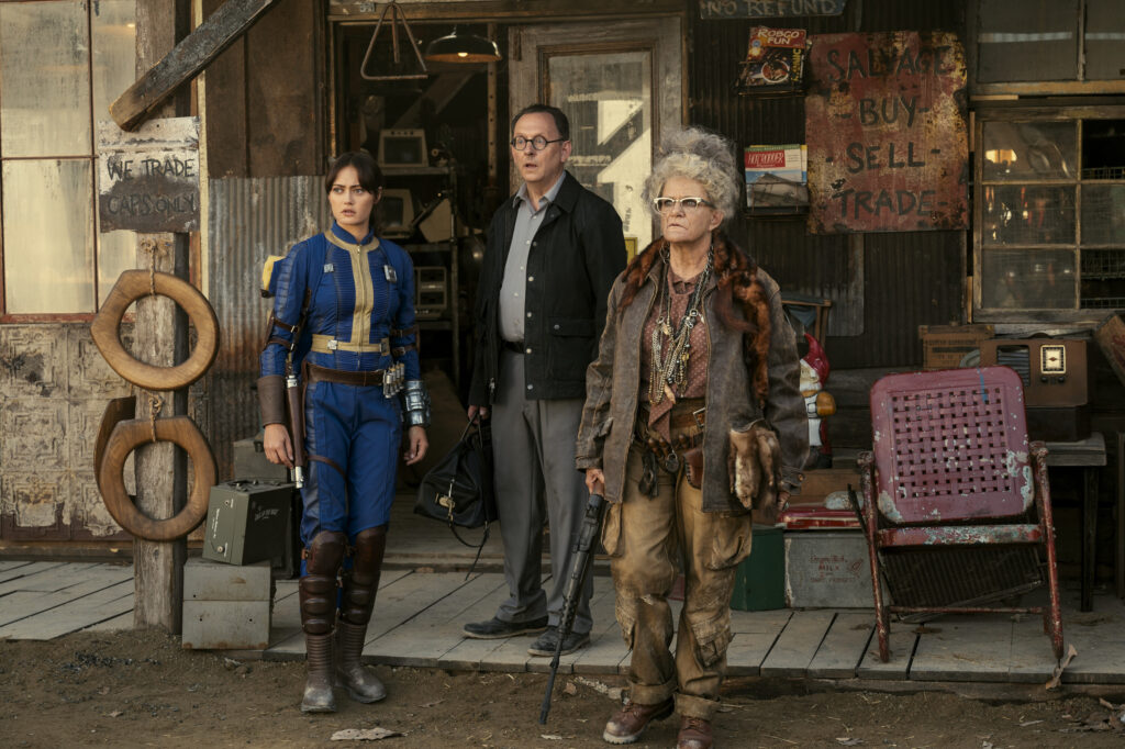 Fallout Season 1 Episode 2, "The Target" | Tell-Tale TV Fallout Season 1 Episode 2. Lucy, Dr. Wilzig, and Ma June, looking at something