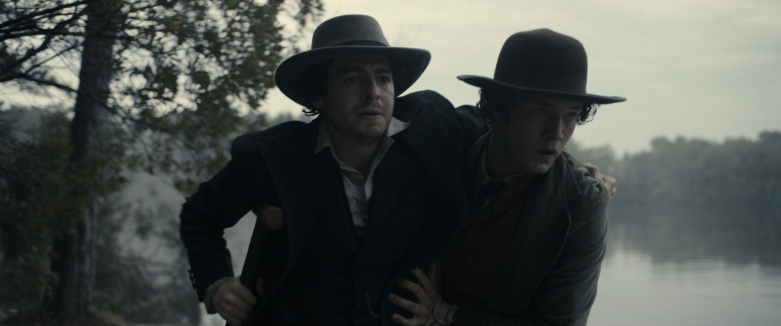 Still from Manhunt Season 1 Episode 5 of Anthony Boyle and Will Harrison pictured outside from left to right with Boyle leaning on Harrison.