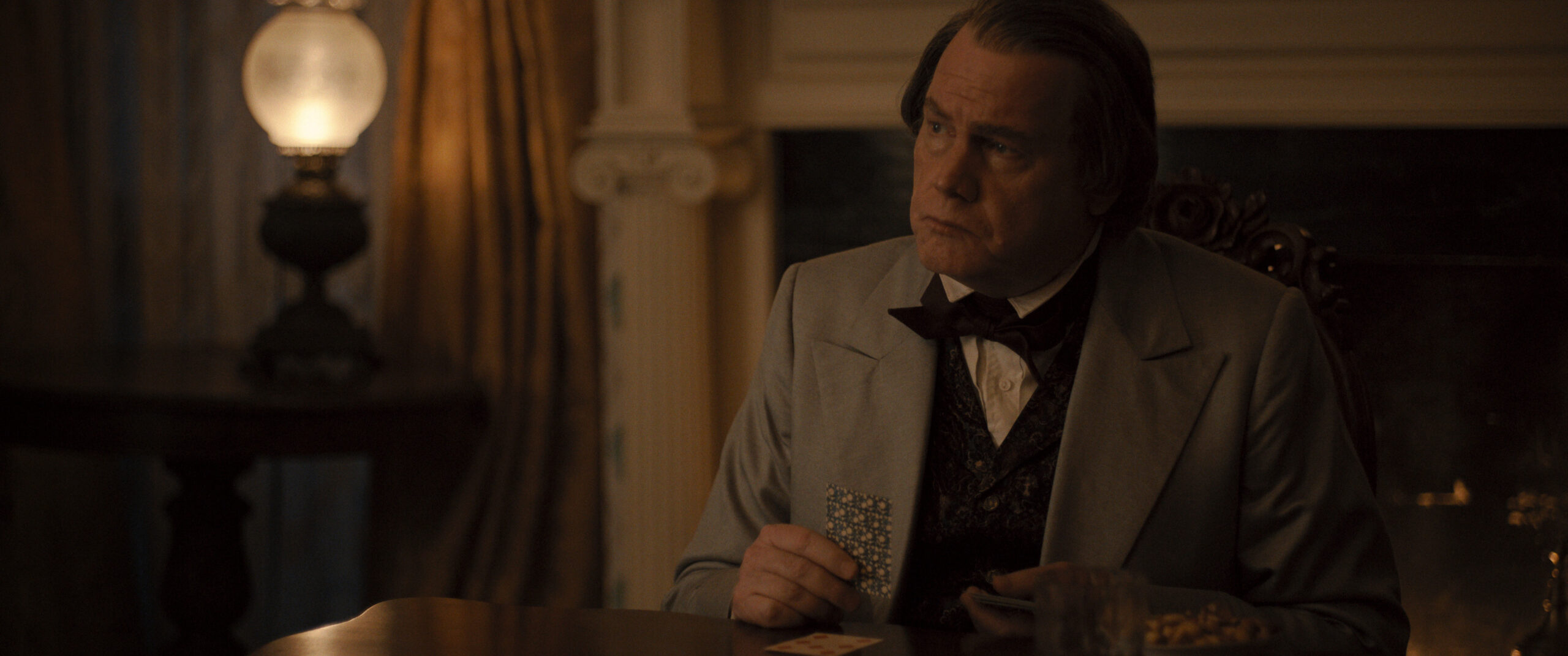 Still from Manhunt Season 1 Episode 5 of Glenn Morshower as Andrew Johnson pictured in a medium shot wearing a light jacket and dark vest and bowtie.