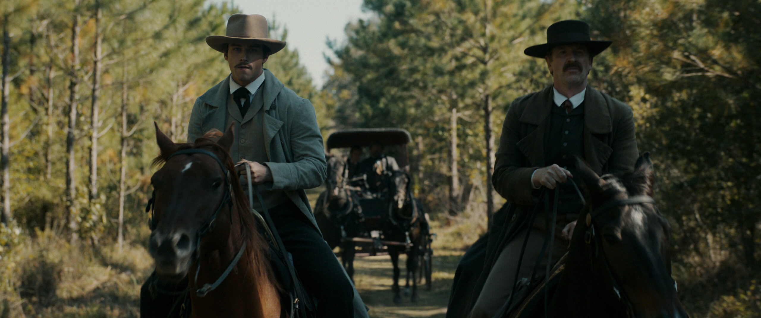 Still from Manhunt Season 1 Episode 6 of Brandon Flynn and Damian O’Hare on horseback pictured from left to right.