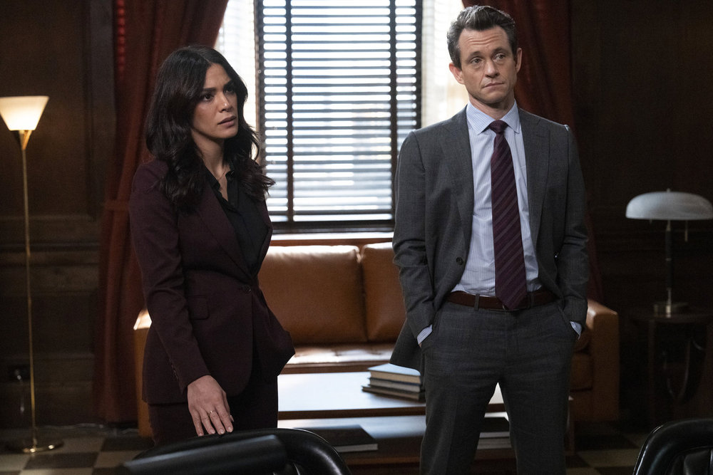 Law & Order Season 23 Episode 9 - Odelya Halevi as ADA Samantha Maroun stands with Hugh Dancy as ADA Nolan Price in DA Baxter's office.