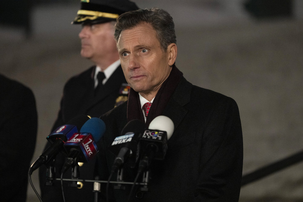 Law & Order - Season 23 | Tell-Tale TV Law & Order Season 23 Episode 10 - Tony Goldwyn as DA Nicholas Baxter stands on the steps of the courthouse behind some microphones speaking to the press.
