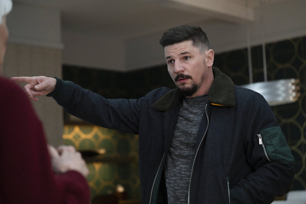 Law & Order: Organized Crime Season 4 Episode 9 - Michael Trotter as Joseph Stabler Jr. stands talking to Mrs. Stabler, mostly out of frame, he is pointing to something behind them.