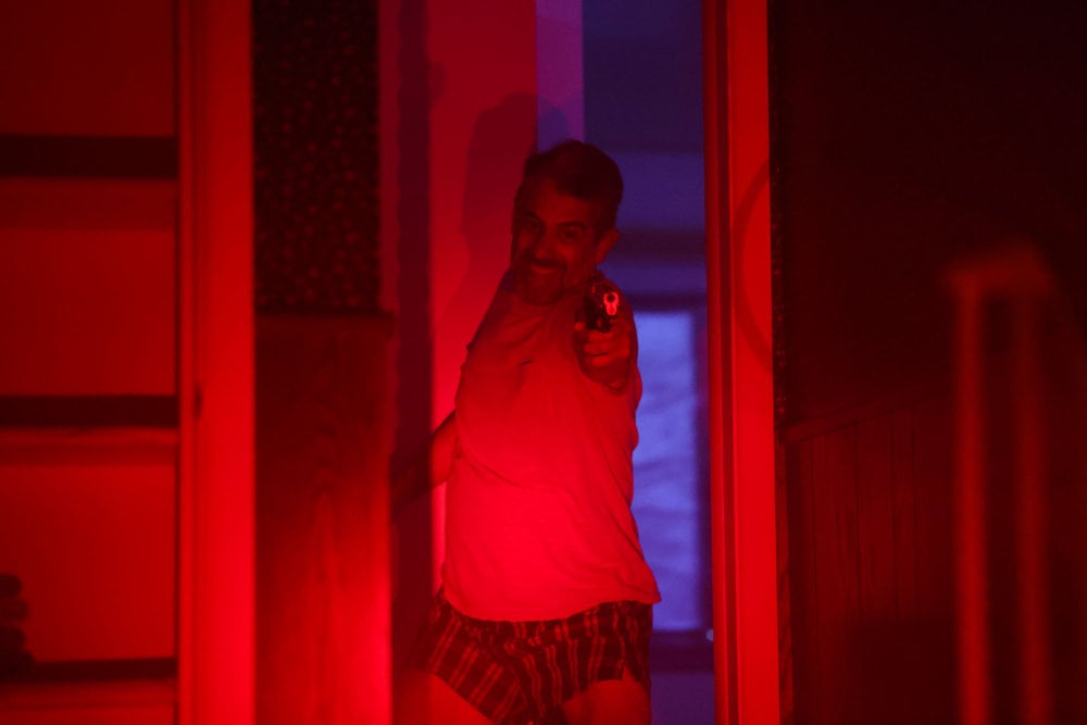 Chicago P.D. Season 11 Episode 10 - Dennis Saldana as Daniel Benitez comes out his front door with a gun raised, the red of the police lights light the scene.