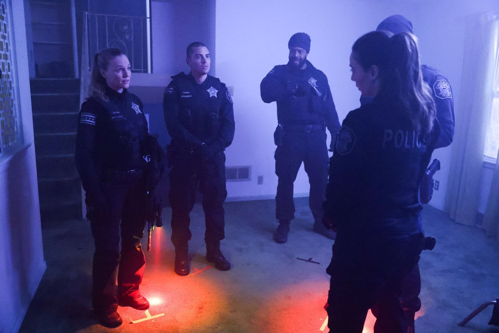 Chicago P.D. Season 11 Episode 10 - Tracy Spiridakos as Hailey Upton, Benjamin Levy Aguilar as Dante Torres, LaRoyce Hawkins as Kevin Atwater, and Marina Squerciati as Kim Burgess all stand in a circle debriefing on location of an arrest.