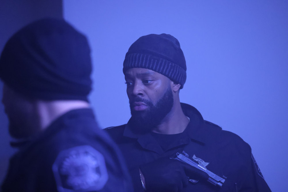 Chicago P.D. Season 11 Episode 10 - LaRoyce Hawkins as Kevin Atwater stands at attention with his gun against his chest.