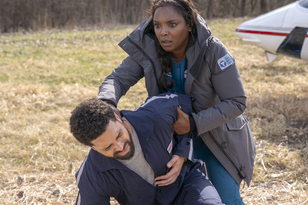 Chicago Med - Season 9 | Tell-Tale TV Chicago Med Season 9 Episode 10 - Henderson Wade as Dr. Loren Johnson is kneeling on the ground, clutching his abdomen in pain while Marlyne Barrett as Maggie Lockwood is behind him supporting him.