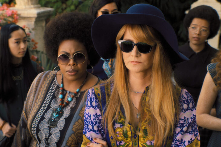 Virginia and Linda wear large-framed sunglasses with flowery tops. They stand among a crowd in a cemetery on Palm Royale Season 1 Episode 7, "Maxine Bags a Prince."