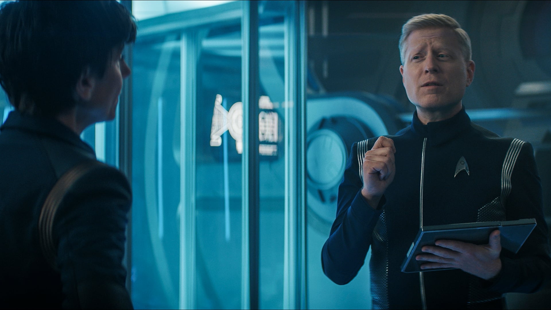 Lt. Cmdr. Paul Stamets wears his blue and silver Starfleet uniform. He stands in engineering on the U.S.S. Discovery while looking bewildered on Star Trek: Discovery Season 5 Episode 4, "Face the Strange."