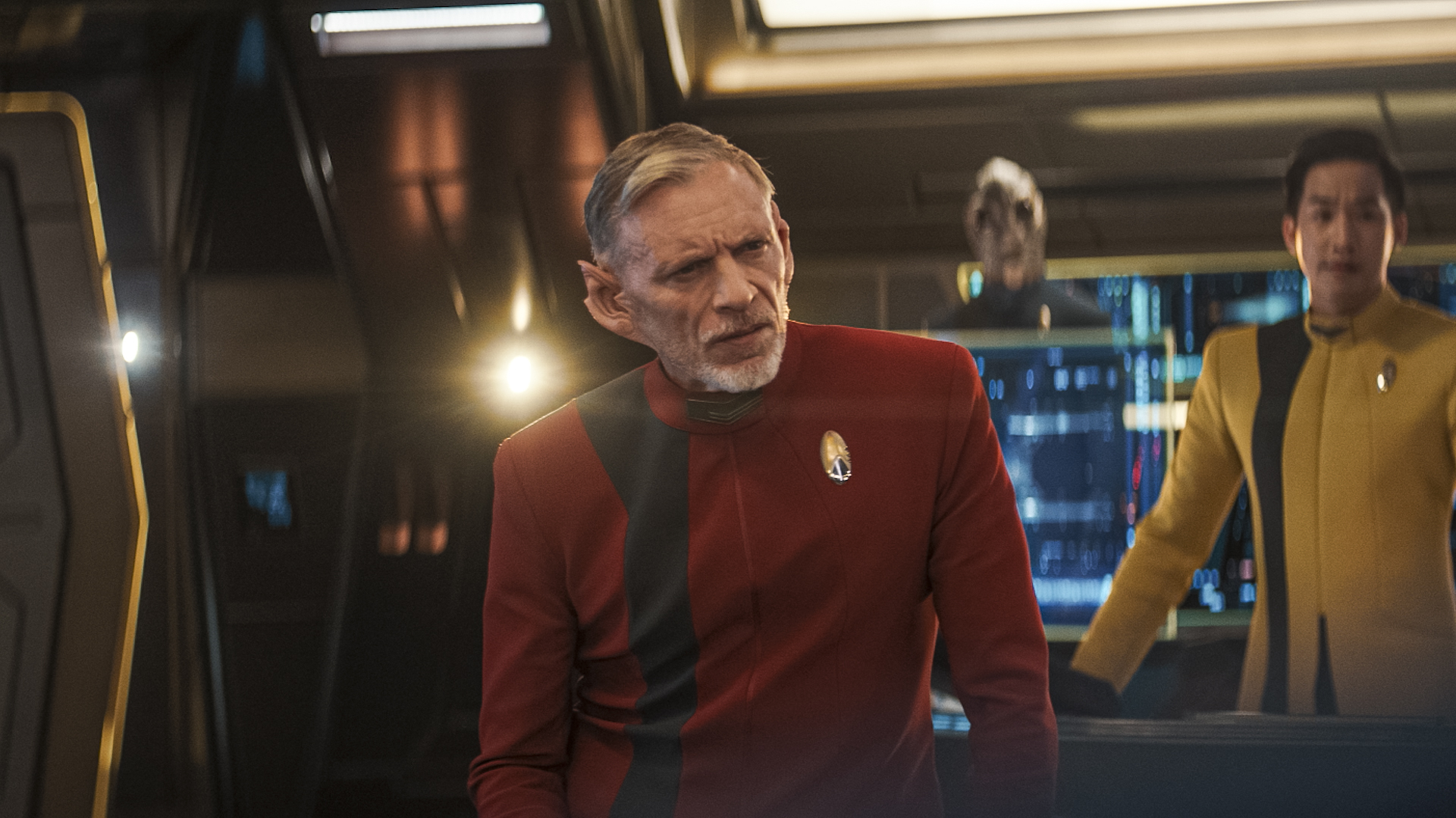 Star Trek: Discovery Season 5 Episode 5 Mirrors | Tell-Tale TV Cmdr. Rayner stands on the bridge of the U.S.S. Discovery while wearing his traditional red Starfleet uniform on Star Trek: Discovery Season 5 Episode 5, "Mirrors."