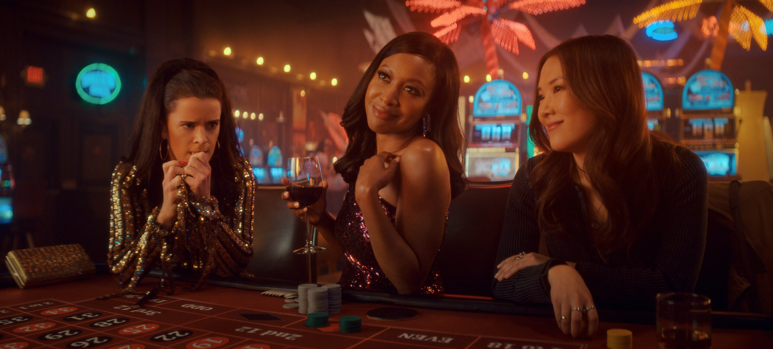 Still from The Big Door Prize of Mary Holland, Gabrielle Dennis and Ally Maki in a casino sitting from left to right at craps table.