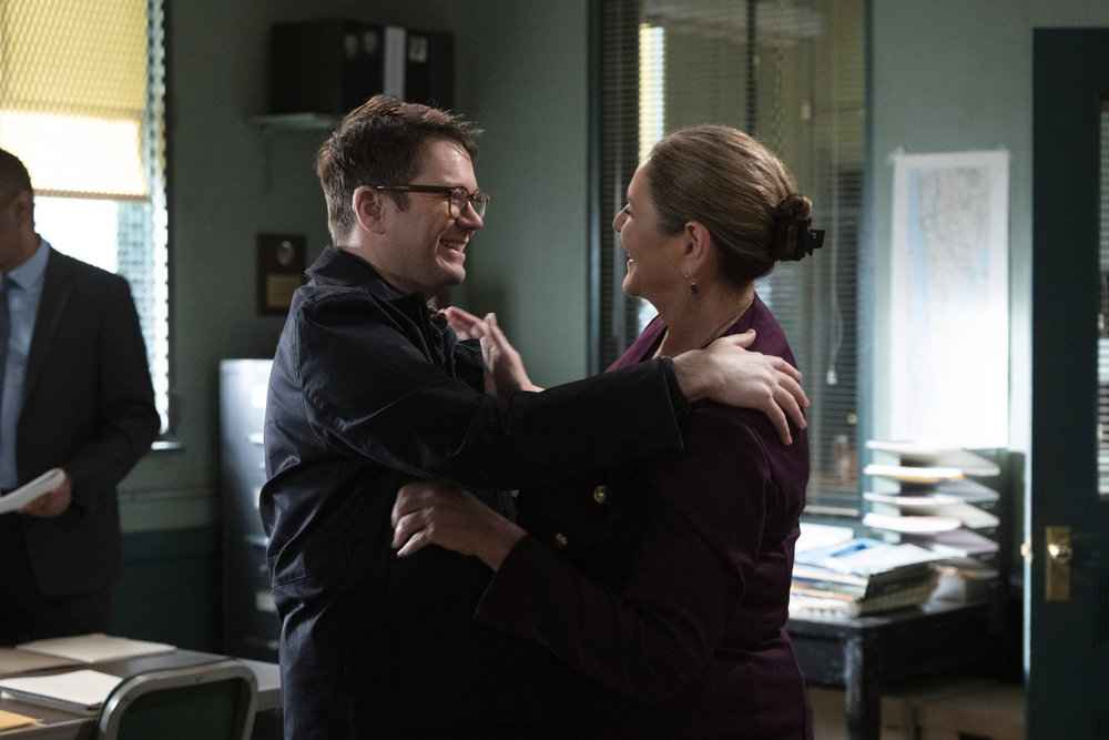 Law & Order - Season 23 | Tell-Tale TV Law & Order Season 23 Episode 11 - James Caverly as Patrick Dixon embraces Camryn Manheim as Kate Dixon, both are smiling.