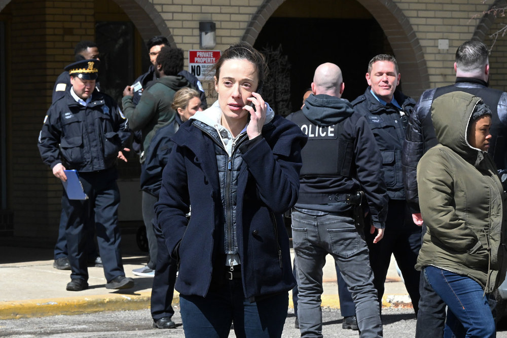 Chicago P.D. Season 11 Episode 12 - Marina Squerciati as Kim Burgess stands amongst a crowd of cops talking on her cell phone.