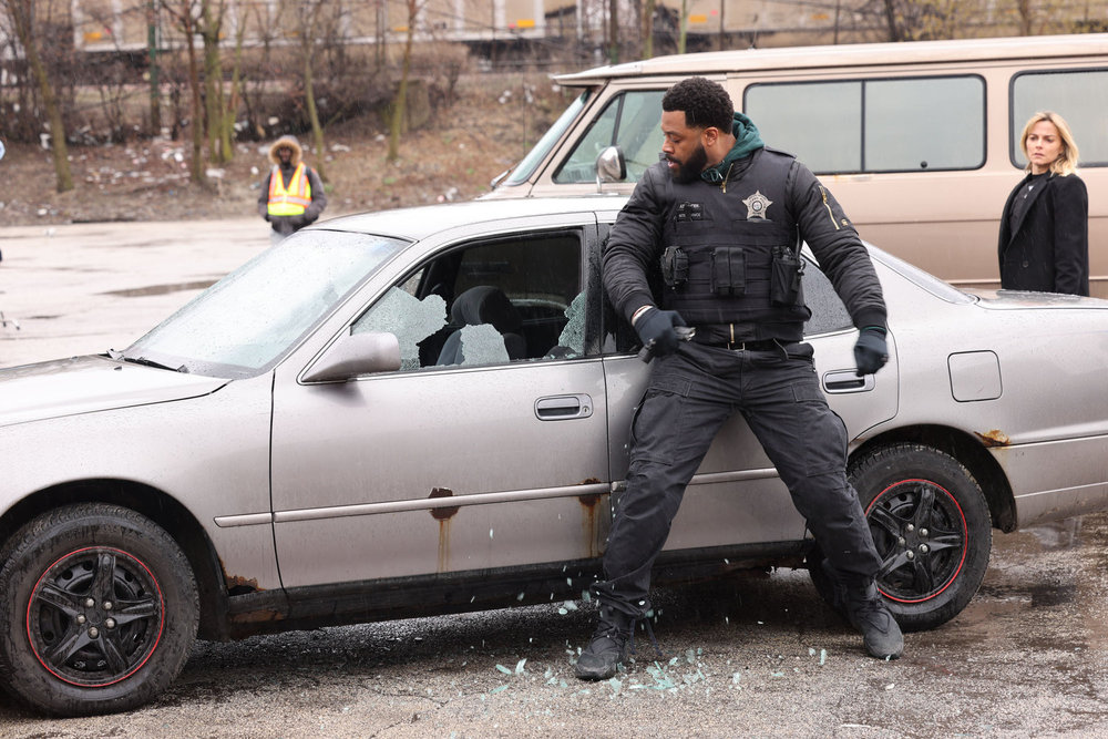 Chicago P.D. - Season 11 | Tell-Tale TV Chicago P.D. Season 11 Episode 13 - LaRoyce Hawkins as Kevin Atwater attempts to search a car by breaking the driver's side window as Bojana Novakovic as Josephine Petrovic stands nearby.