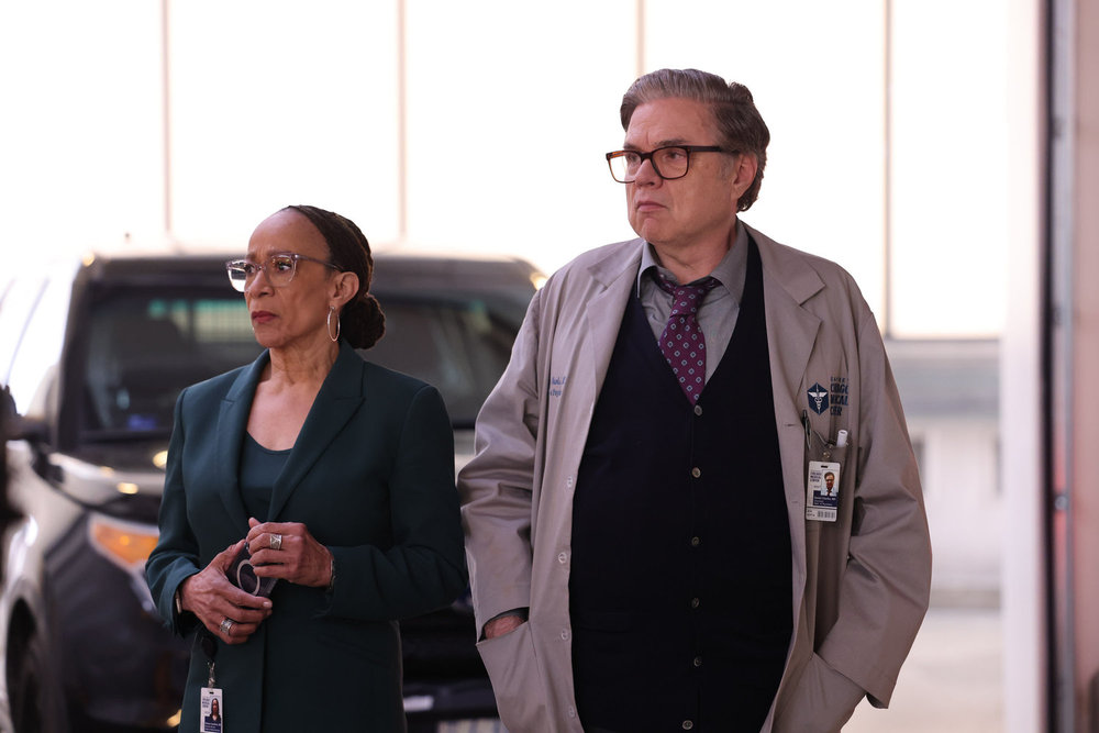 Chicago Med Season 9 Episode 13 - S. Epatha Merkerson as Sharon Goodwin and Oliver Platt as Dr. Daniel Charles stand together looking concerned.