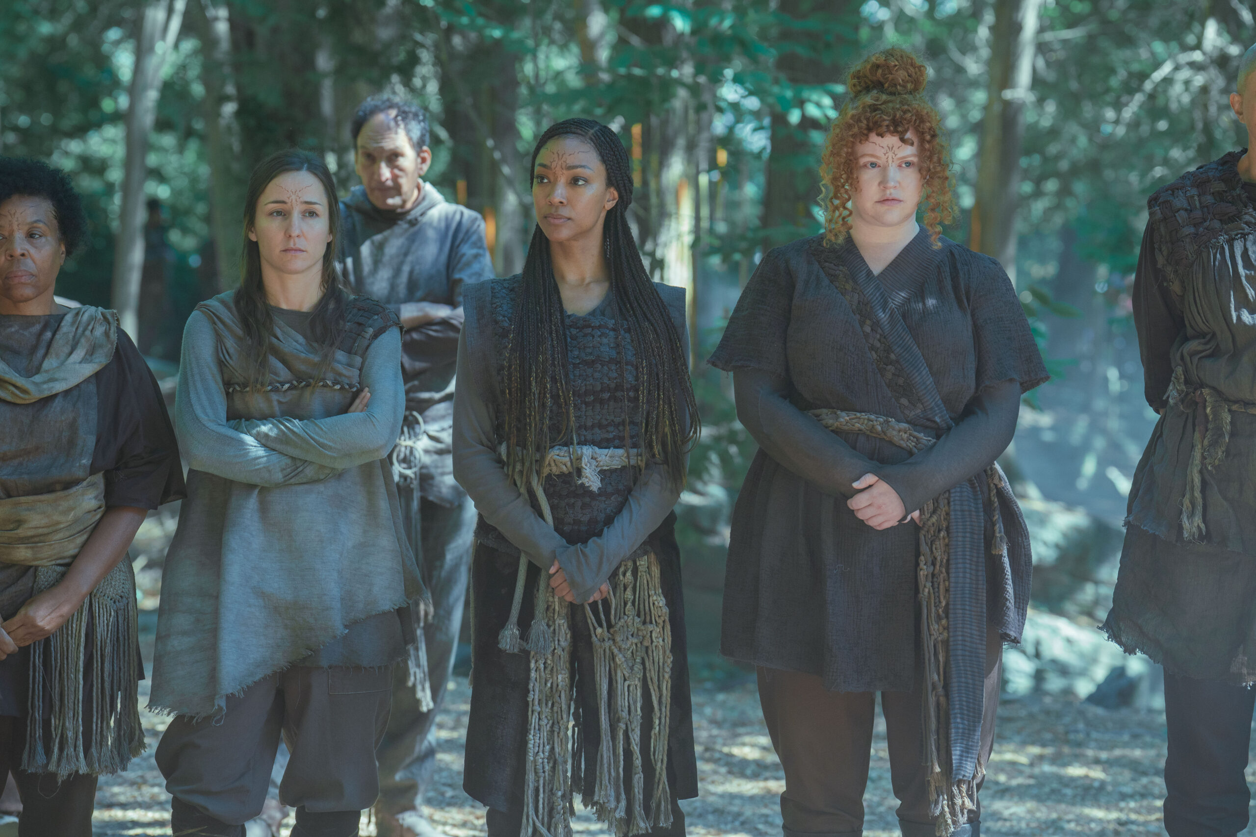 Captain Burnham and Lt. Tilly wear traditional Halem'nite clothing, which consists of rough-spun dark brown fabric and leather. They stand in the woods on the planet Halem'no on Star Trek: Discovery Season 5 Episode 6, "Whistlespeak."