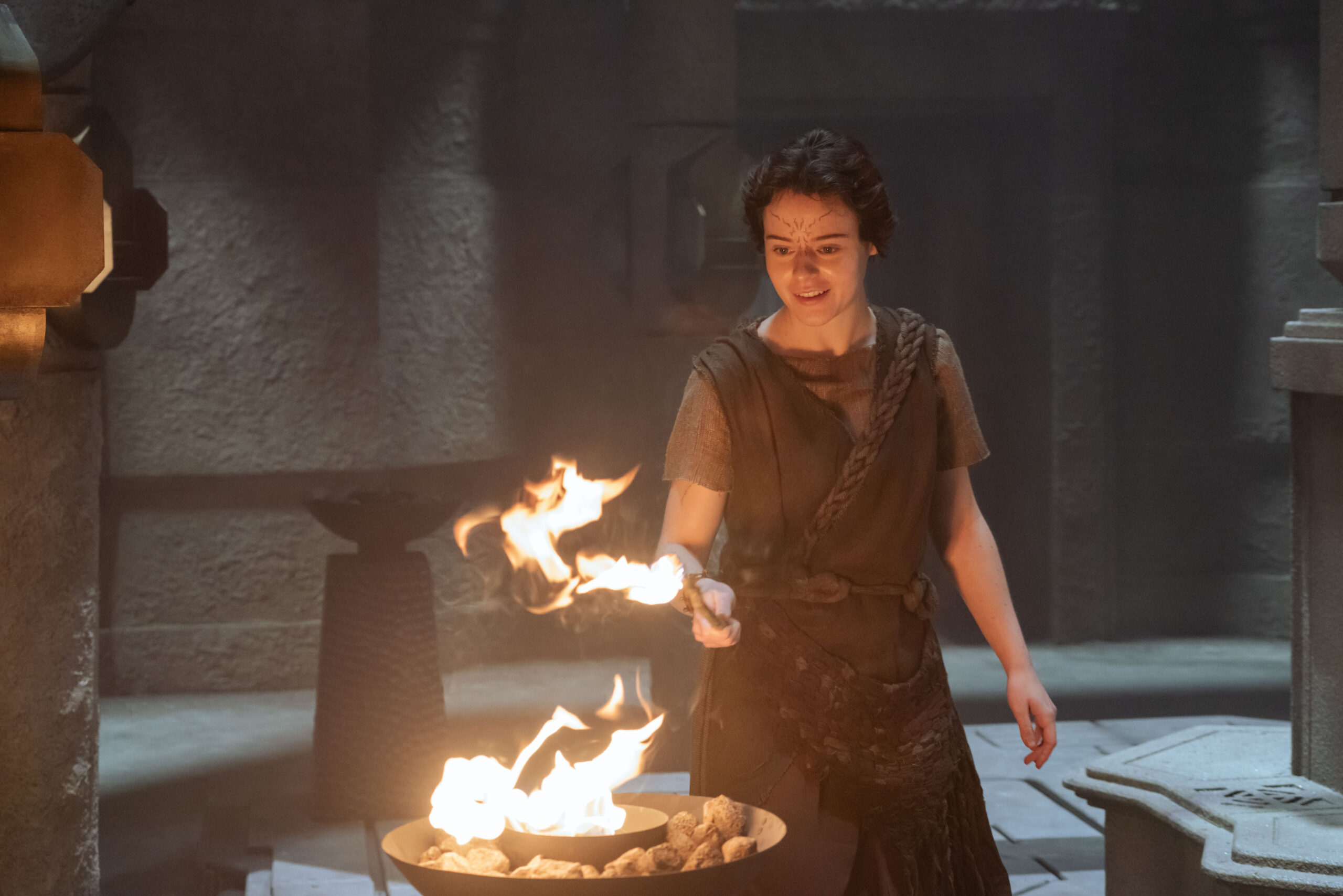 Ravah, a Halem'nite, wears clothing consisting of rough-spun dark brown fabric and leather. She lights a fire pit on Star Trek: Discovery Season 5 Episode 6, "Whistlespeak."
