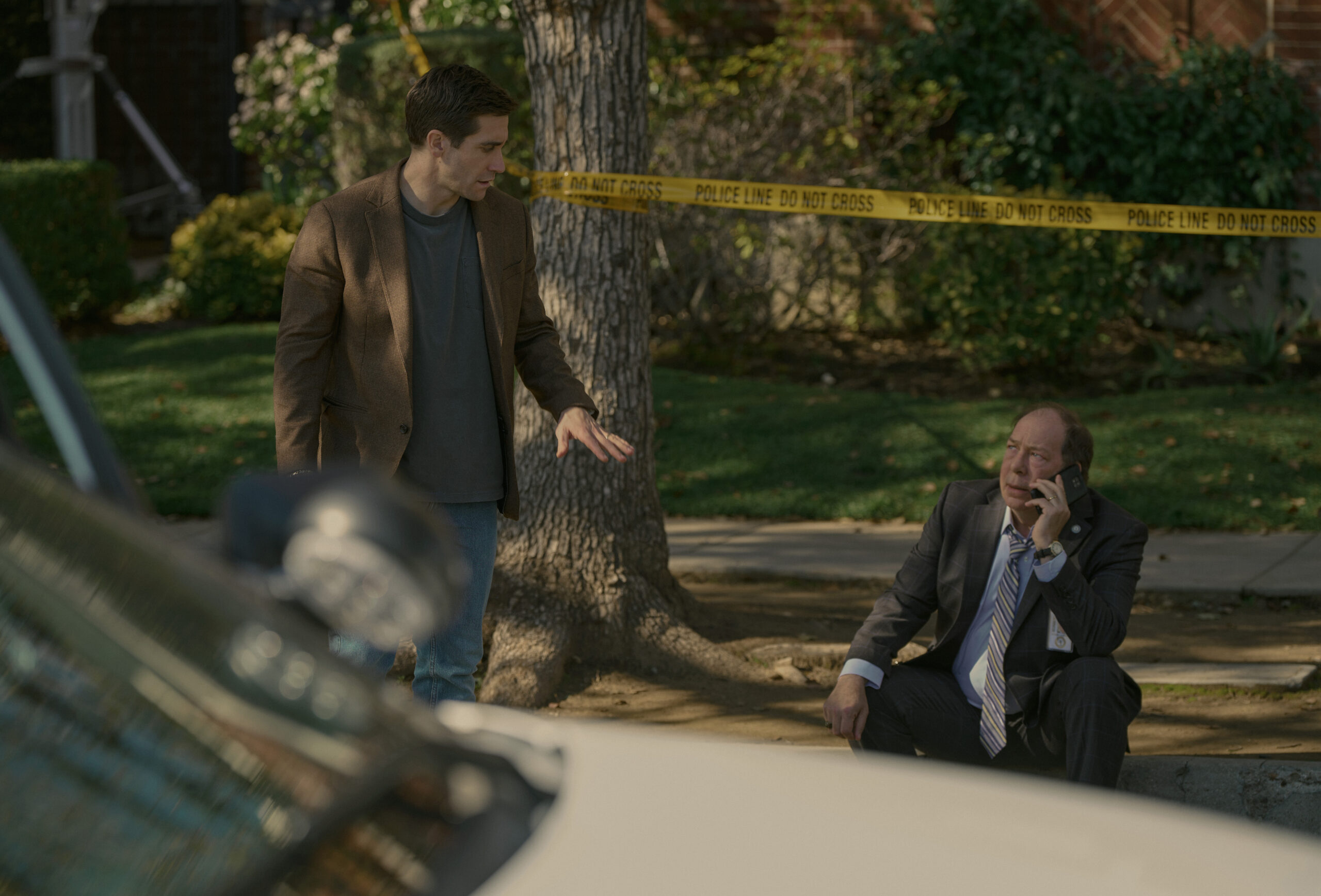 Jake Gyllenhaal on Presumed Innocent talking to a man sittin on the sidewalk.