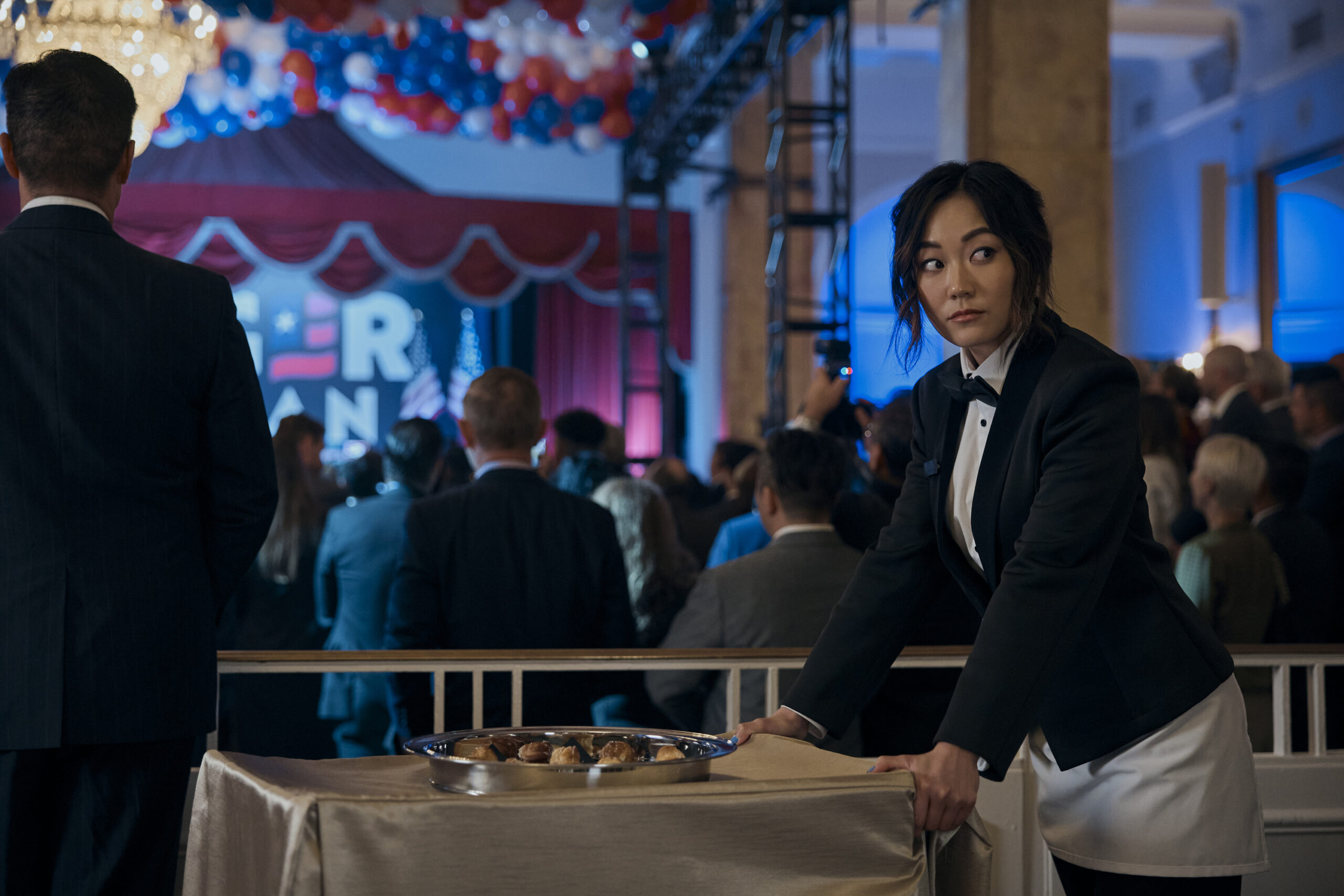 Still from The Boys Season 4 Episode 1 of Karen Fukuhara as Kimiko dressed as a caterer pushing a small cart.