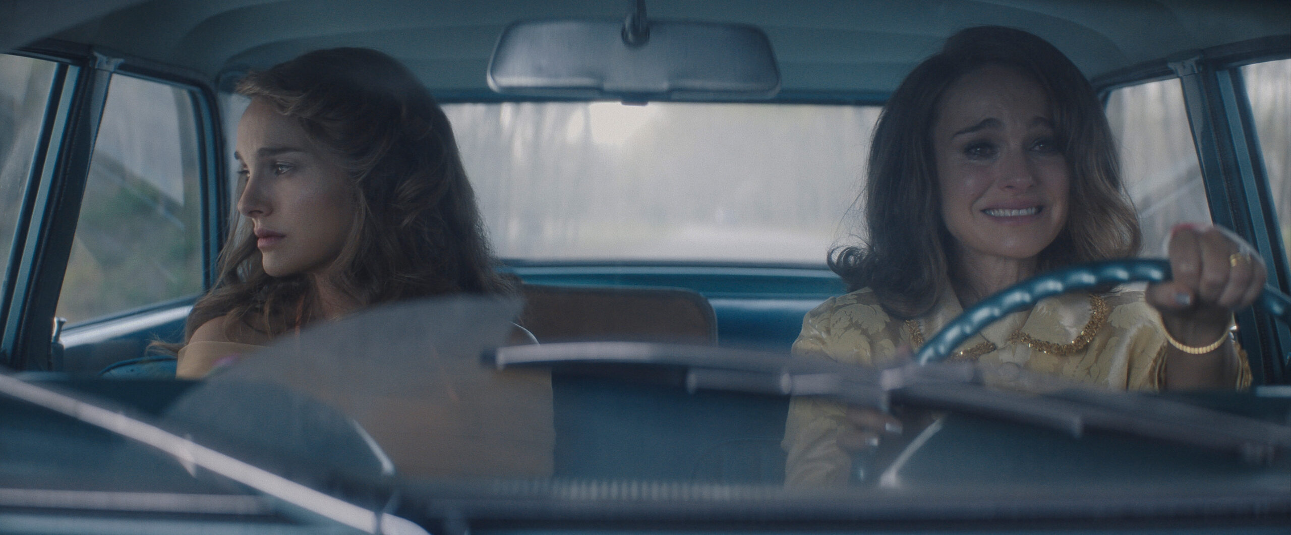Still from Lady in the Lake Season 1 Episode one of two different version of Natalie Portman in a car pictured from left to right. One is driving the car and the other is looking out the passenger window.