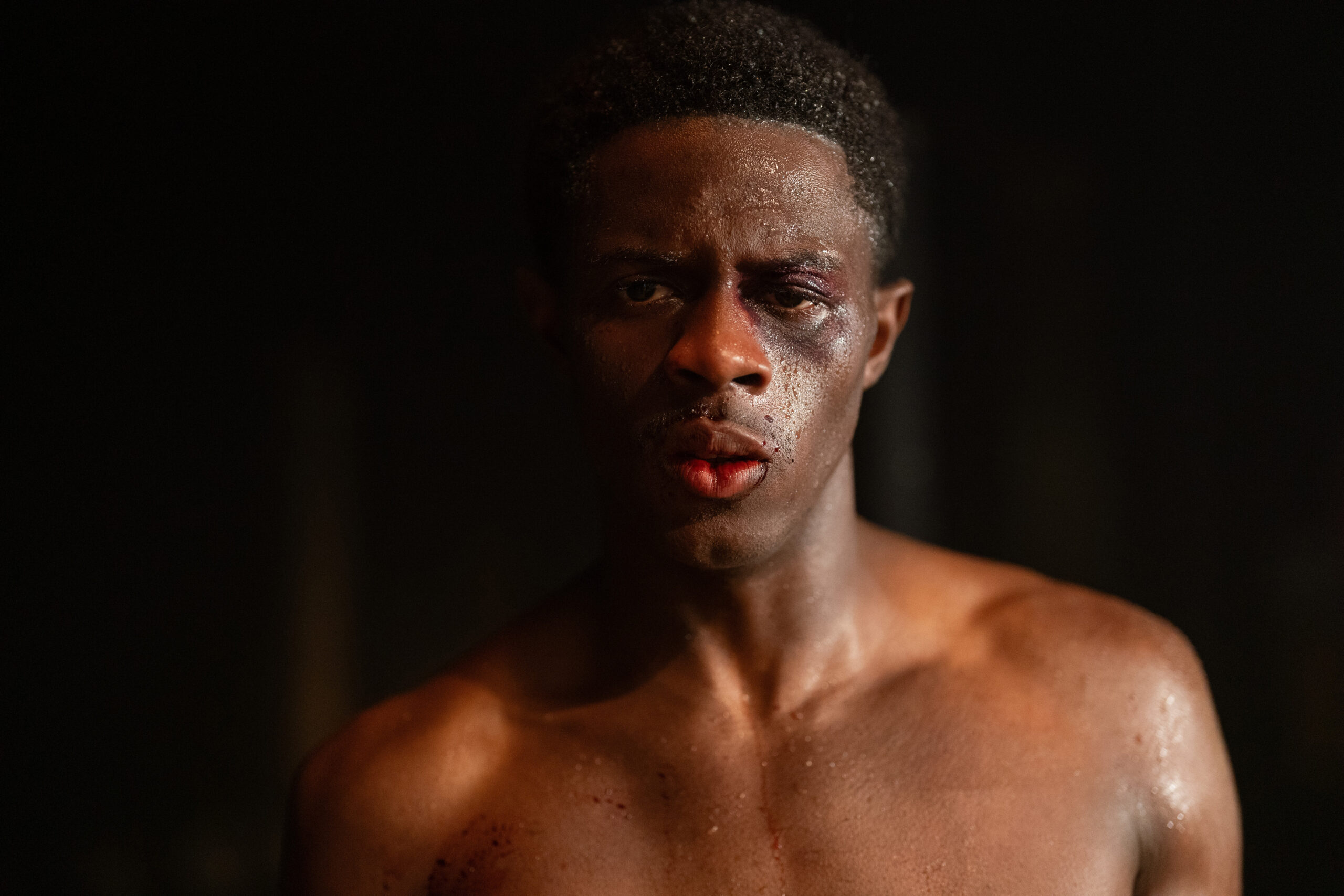 Still from Lady in the Lake of Josiah Cross in a medium shot with no shirt on and perspiring looking straight ahead.