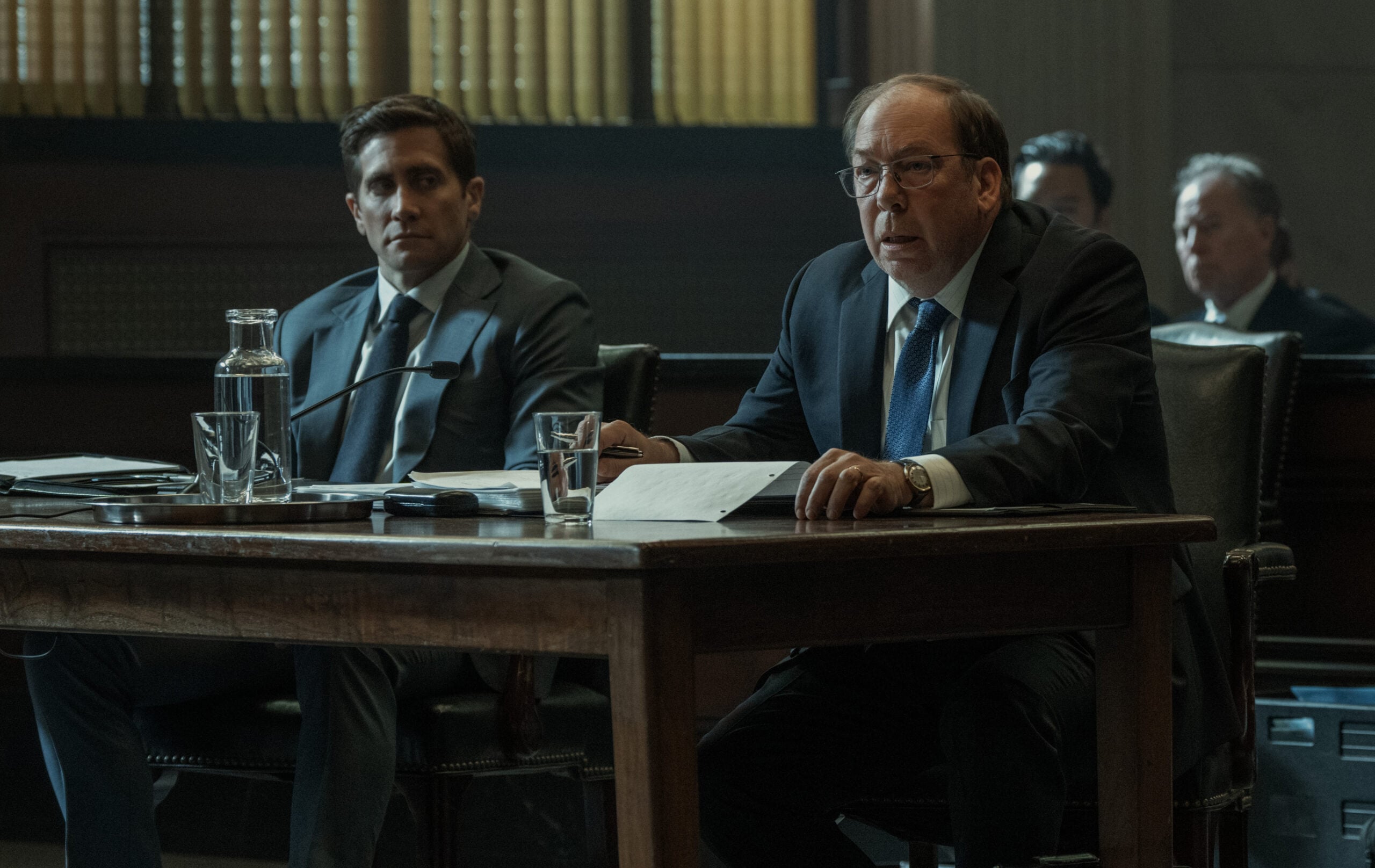 Jake Gyllenhaal sitting next to Bill Camp in court.