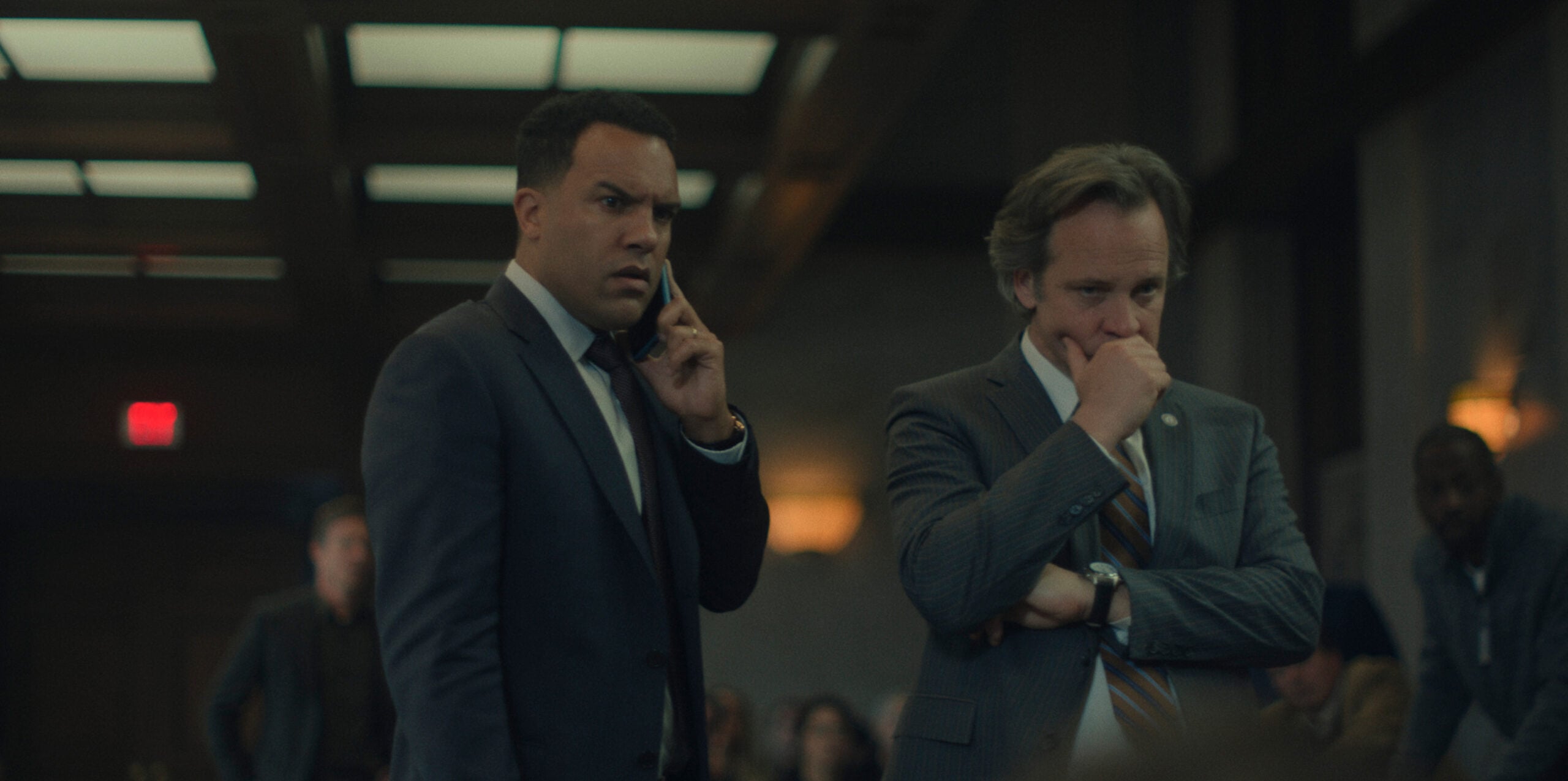 O-T Fagbenle and Peter Sarsgaard standing in court while Fagbenle talks on the phone.
