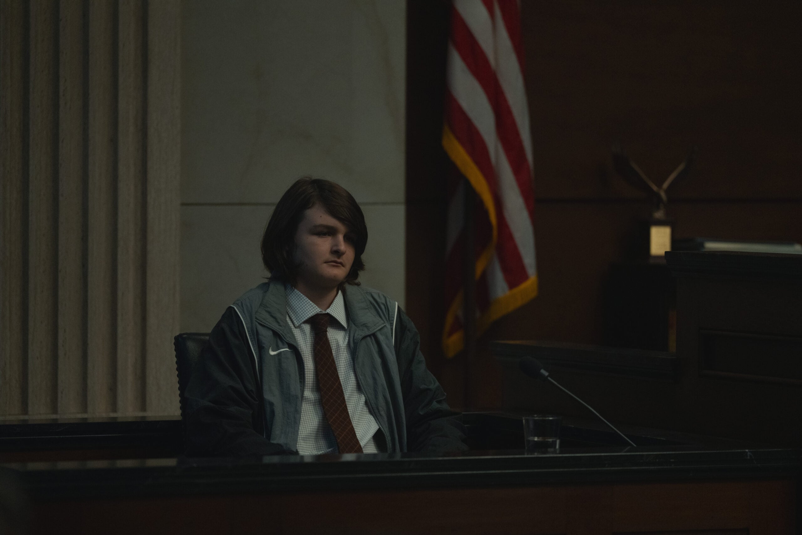 Tate Birchmore in the witness stan in front of an American flag.