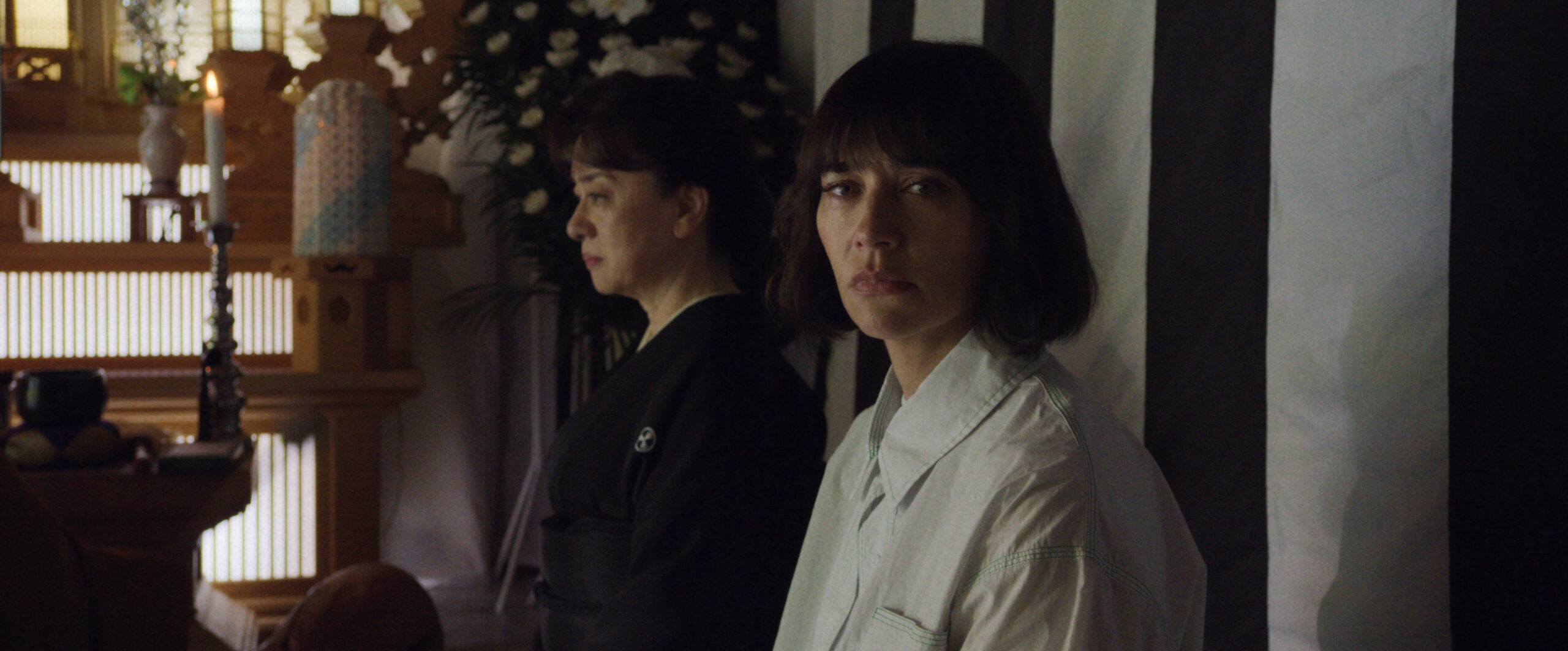 Sunny Season 1 Episode 3 Mmmm Hinoki | Tell-Tale TV Noriko Sakamoto and Suzie sit during a funeral service. Suzie looks at someone off-screen in surprise on Sunny Season 1 Episode 3, "Mmmm Hinoki."