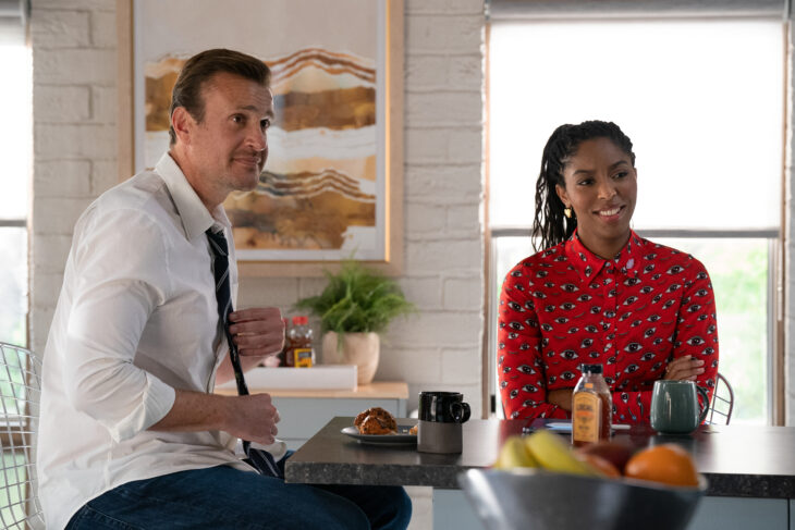 Jimmy and Gaby sit in the breakroom of their therapy practice while smiling and looking at something off-screen on Shrinking Season 2 Episode 2, "I Love Pain."