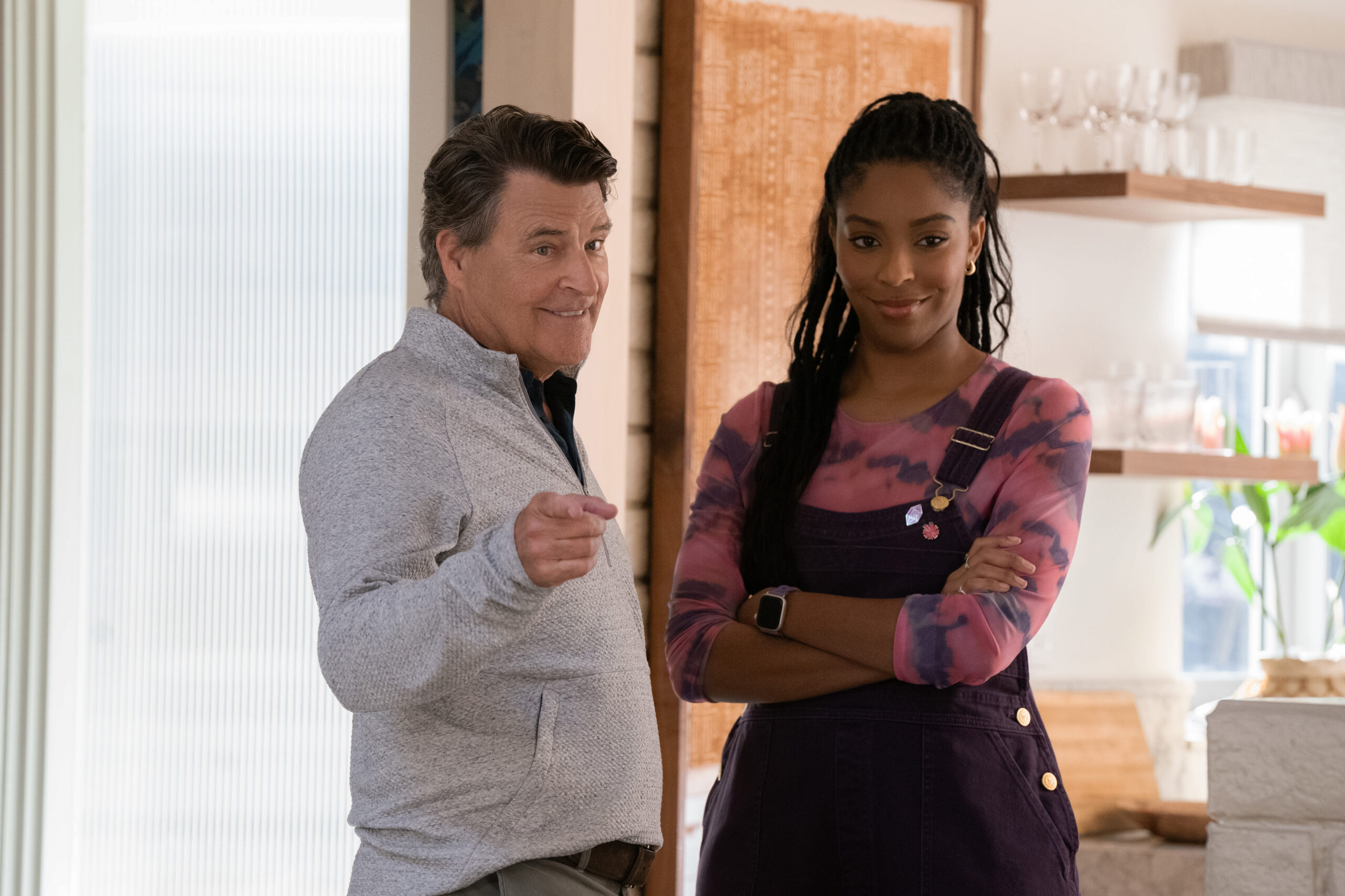 Shrinking Season 2 Episode 4 Made You Look (3) | Tell-Tale TV Derek points at someone out of frame while smiling as Gaby stands beside him, her arms crossed, on Shrinking Season 2 Episode 4, "Made You Look."