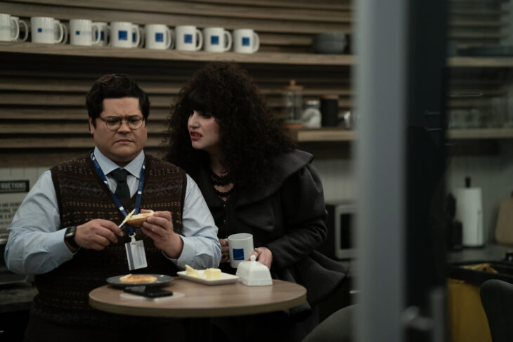 Nadja leans over Guillermo while looking menacing. Both stand in the employee breakroom of a financial firm on What We Do in the Shadows Season 6 Episode 2, "Headhunting."